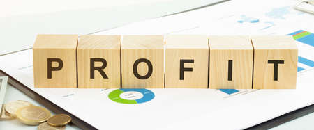 profit text written on wooden block with stacked coins on gray backgroundの写真素材