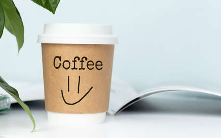 A cup of coffee with the inscription Coffee and an emoticon on the desktop. Coffee break concept.の写真素材