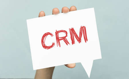 card in hands with the text CRM on a light blue background.の写真素材