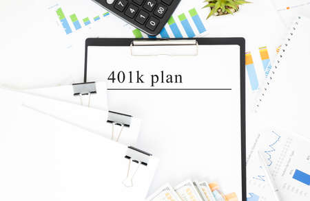 Text 401K Plan is written on a notebook with a pen and a magnifying glass lying on the table. Business concept.の写真素材