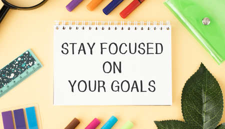 Inspirational quote - Stay focused on your goals. With text message on white paper book, pen, a cup of morning coffee, flower.の写真素材