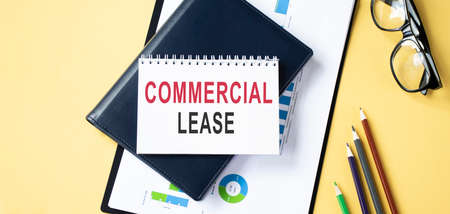 glasses, coffee mug and notebook with COMMERCIAL LEASE word on wooden table. business conceptualの写真素材