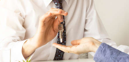 Real estate agent holding a key and asking costumer for contract to buy, get insurance or loan real estate or property.の写真素材