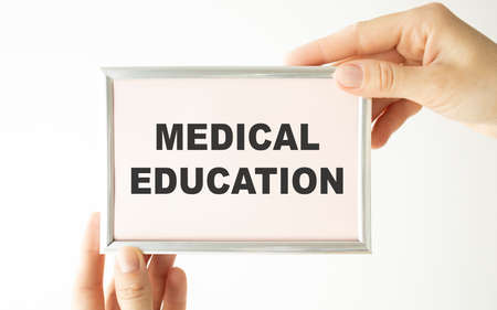 Hands holding clipboard with text medical education on a sheet of paper on a white backgroundの写真素材