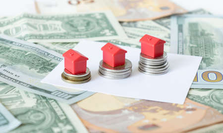 Minature houses resting on pound coin stacks concept for property ladder, mortgage and real estate investmentの写真素材