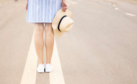 a young girl stands on the road at the dividing strip in a pink hat and white sneakers, sunset soldier, streetの写真素材