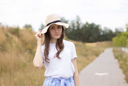 a young smiling girl stands with a hat in her hands, covering her face.の写真素材