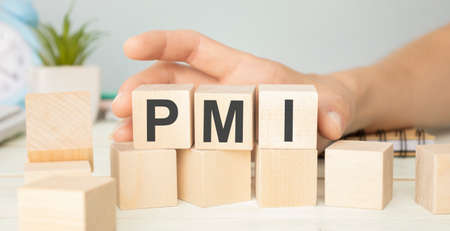 Text PMI on wood cube with gold bar and newspaper on the table, economic data conceptの写真素材