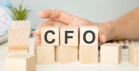CFO Chief Financial Officer written on a wooden cube in front of a laptopの写真素材