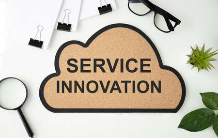 Cloud-shaped board with text Service Innovation on a white table with documents.の写真素材