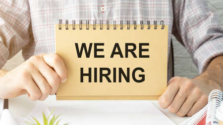Businessman holds a card with the text We Are Hiring. Business concept.の写真素材