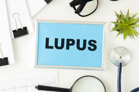 Medical concept. Top view of stethoscope and syringe with notebook written with LUPUS on wooden background.の写真素材