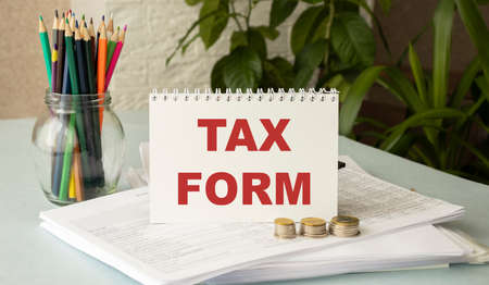Tax-filling concept. Text Tax Form on note paper with the US IRS 1040 form, pen and glassesの写真素材