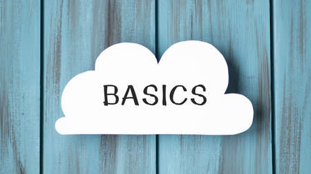 White flap card with the text: Basics on a wooden background.の写真素材