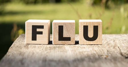 Flu concept. located on wooden cubes on a background of a medical mask.の写真素材