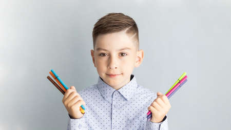Back to school. Happy smiling boy with thumb up. Child from elementary school in uniform. Kid indoors of the class room with blackboard on a background. Funny kidの写真素材