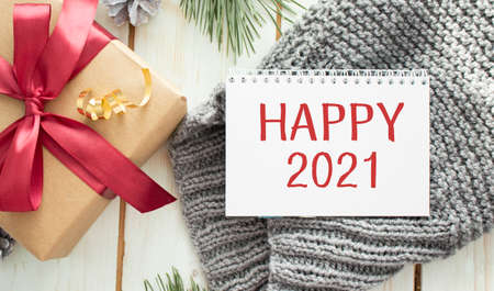 Happy New Year 2021 gilded text in frame. Vine, glasses, plates, fork, knife. Xmas decorations and garland. Flat lay in golden, pink and purple on linen textile.の写真素材