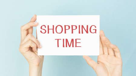 blank sheet of paper with text Time to shop on hand isolated on blue backgroundの写真素材