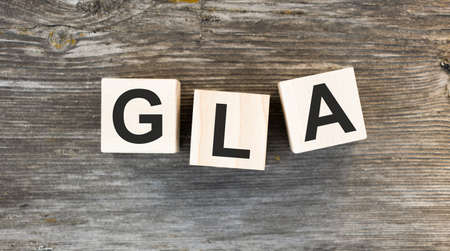 The word GLA which is made from wooden cubes. Hands in a blue glove. Isolated on WHITE background.の写真素材