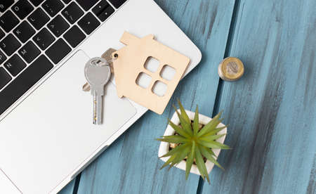 Mini house figurine with keys on an pink desk.の写真素材