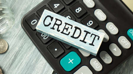 CREDIT with wooden block on cash money with calculator, key and mini house. Real Estate Concept - House with text on wooden blockの写真素材