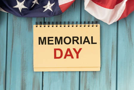 the text memorial day written in a chalkboard and a flag of the United States, on a rustic wooden backgroundの写真素材