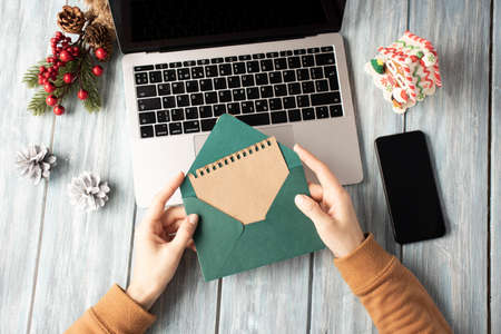 Woman holding green envelope over laptop, Christmas atmosphere in the officeの写真素材