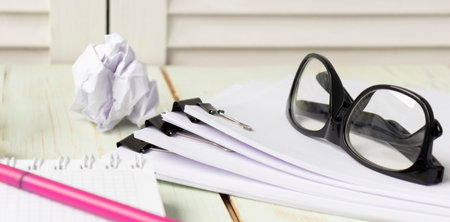 Hands of businessman hold pen for work in stacks of paper files, information search for business...