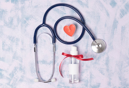Toy heart and medical stethoscope and antiseptic on a blue background, top viewの写真素材