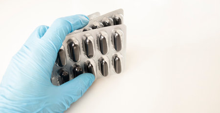 Male hand in a medical glove holds a handful of yellow pills. Isolated on white photo.の写真素材
