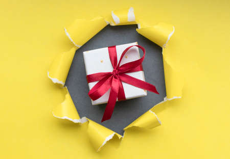 gift box with red ribbon bow, isolated on yellowの写真素材