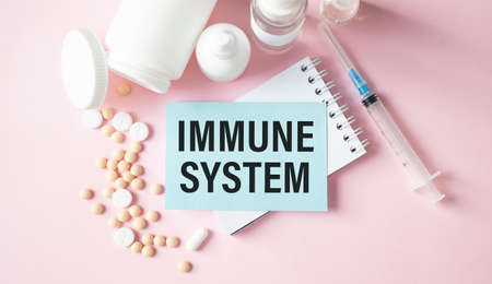 Immune system. Pills and syringe on pink desk with immune system word as medical concept.の写真素材