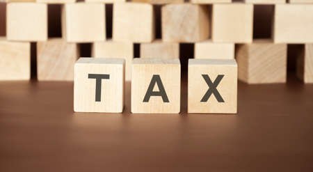 Word TAX. Wooden small cubes with letters isolated on white background with copy space available....