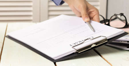 Close-up of colleagues working together at desk in office discussing papers