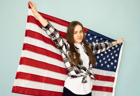 young beautiful woman holding USA flag on a blue background