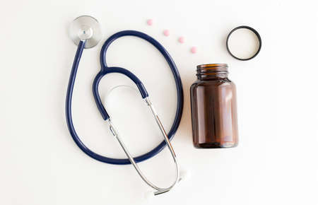 Pills, medical bottle and stethoscope on a white table.の写真素材