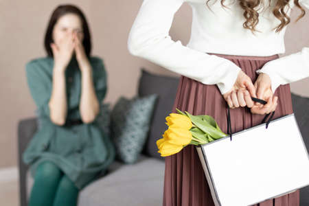 Girl holding flowers for mother behind her back, closeup