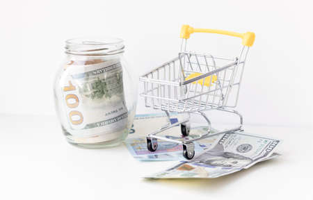glass jar filled with money and miniature grocery cart