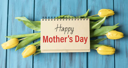 Mother's day text on notepad with yellow flowers. Happy mothers day