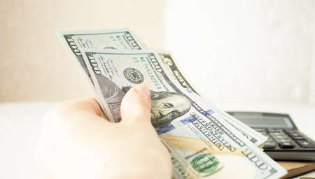 closeup of Asia business, workingwoman, people holding Us dollar banknotes money, using calculator...