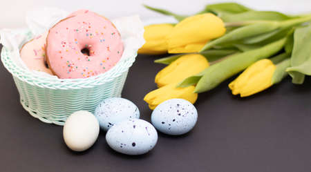Easter background blue. Colorful egg with tape ribbon, spring tulips on dark rough stone background in Happy Easter decoration. Flat lay, top view.の写真素材