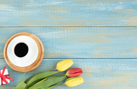 Tulips and coffee cup on wooden table. Top view with copy spaceの写真素材