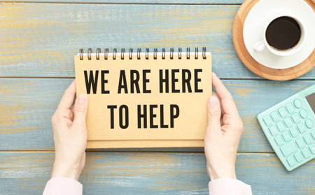 WE ARE HERE TO HELP written on a white sheet held by a person. Sponsorship conceptの写真素材
