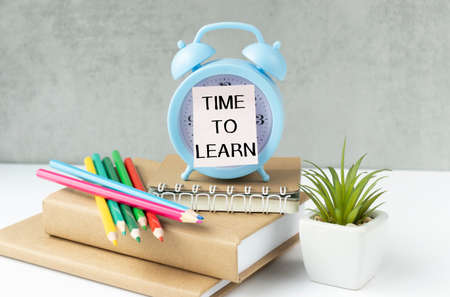 Time to Learn text on Blue alarm clock on a background of books. Education concept. It's time to...