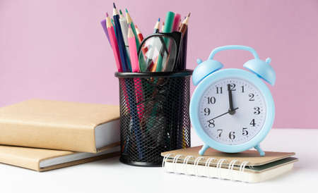Alarm clock on wooden table on background in classroom, back to school concept