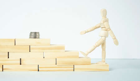 A wooden man walking up the steps to the coins. Business strategy and financial development concept.の写真素材
