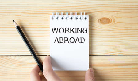 Businessman holding a white notepad with text working abroad , business conceptの写真素材