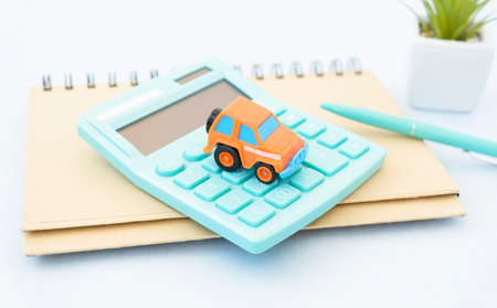 Black ballpoint pen, calculator and red car on paper form, Blur with bright background, out of focusの写真素材