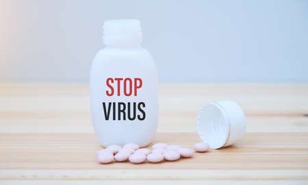 STOP VIRUS text on a medicine jar with scattered pillsの写真素材