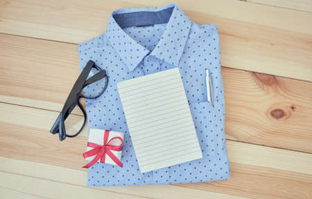 Businessman shirt on white with notepad and glasses on wooden background